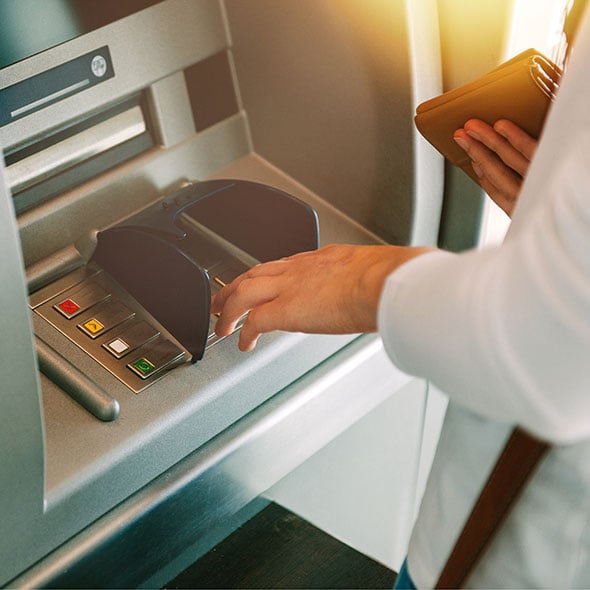 Woman is using an ATM with the CO-OP ATM network with PCU credit union.