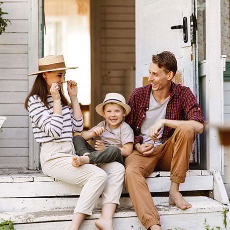 Cheerful family sitting on the porch of their new house after saving with First Time Homebuyer Savings Account at PCU