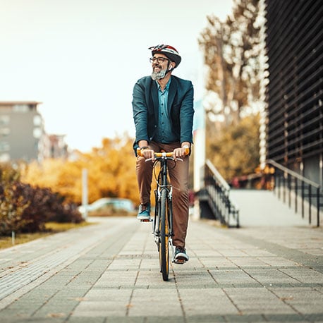 Man riding his bike through a city who is happy because he has a money market savings account with PCU.
