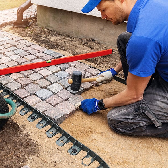 Man building a stone pathway financed with his personal line of credit from CCCU.
