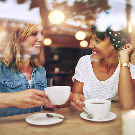 Friends at cafe together who enjoy simple checking account from PCU.